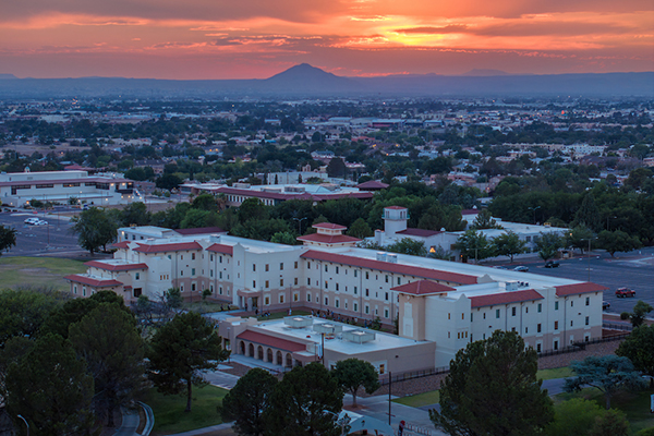 Juniper hall in the foreground with the campus and mountains in the background at sunset